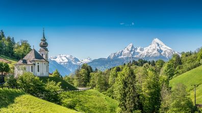 Vit kyrka, gröna ängar och snötäckta berg i Bayern, Tyskland