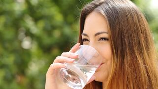 Kvinna dricker ett glas vatten