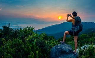 ung kvinna på bergstoppen tar en bild av utsikten