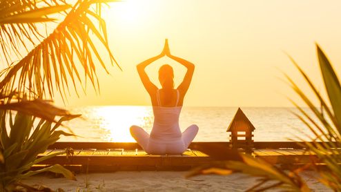 Ung kvinna praktiserer yoga vid soluppgång