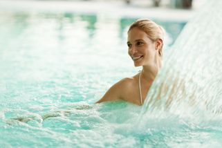 En kvinna är glad över en vattenstråle i en pool på ett spa-hotell i Tyskland