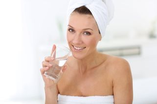 Kvinna i handduk dricker vatten